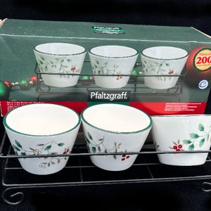May include: Set of four white ceramic bowls with a green and red holly design. The bowls are on a black metal rack. The box says "Pfaltzgraff" and "Holiday 200".