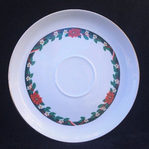 May include: White ceramic serving platter with a gold rim and a Christmas-themed design. The design features a wreath of holly, poinsettia flowers, and red ribbon.