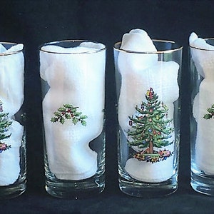 May include: Set of four clear glass highball glasses with a gold rim. Each glass features a Christmas tree design with green, red, and gold accents.