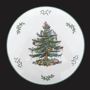 May include: A white ceramic plate with a green rim and a festive Christmas tree design. The tree is decorated with ornaments and topped with Santa Claus. Presents are at the base of the tree, and sprigs of holly and mistletoe are around the plate's edge.