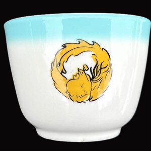 May include: A white ceramic bowl with a blue rim and a yellow and black stylized bird design.