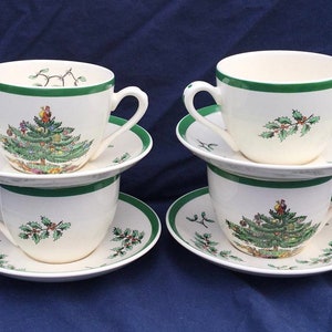 May include: Set of four white ceramic teacups and saucers with a green trim and a Christmas tree design. The cups and saucers feature a green holly design.