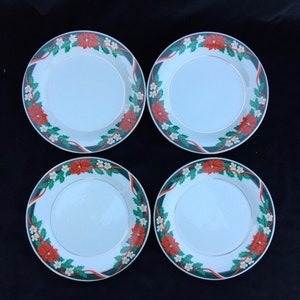 May include: Set of four white ceramic dinner plates with a green, red, and white Christmas floral design. The plates have a gold trim.