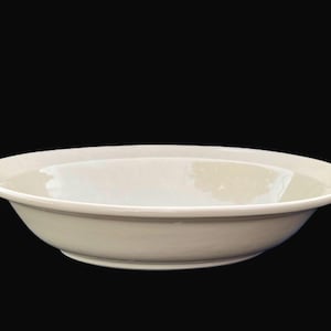 May include: A cream-colored, shallow ceramic bowl with a wide rim. The bowl has a simple, elegant design and is suitable for serving soups, salads, or other dishes. The bowl is set against a black background.