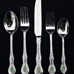 May include: Set of five silver-plated Christmas tree flatware, including a knife, two forks, and two spoons. Each piece features a green Christmas tree design on the handle.