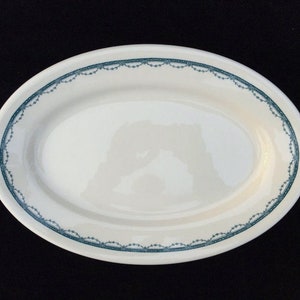 May include: A white oval serving platter with a blue and white decorative border.