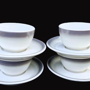 May include: Set of four white ceramic teacups and saucers with a gray ombre design. The cups and saucers are stacked on top of each other.