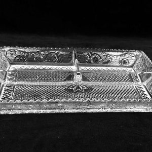 May include: A clear glass serving dish with four divided sections. The dish has a decorative, raised pattern around the edges.