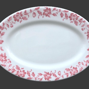 May include: Oval white serving platter with a floral design in shades of pink. The flowers and leaves create a border around the edge of the platter. A classic piece for serving food.