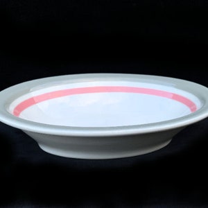 May include: A white ceramic bowl with a light gray rim and a single pink band around the inside.