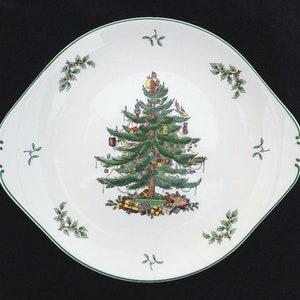 May include: White, square-shaped serving platter with a green trim and handles. The center features a detailed Christmas tree design with ornaments, gifts, and Santa Claus. Holly and mistletoe accents are placed around the rim.