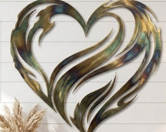 Puede incluir: Una gran escultura de metal en forma de corazón para pared, con un diseño abstracto similar a llamas y un acabado multicolor. La superficie muestra tonos mezclados de bronce, oro y verde azulado, con texturas metálicas y líneas curvas.