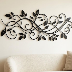 May include: A matte black metal wall art piece featuring a horizontal, elongated design of interconnected swirling vines and pointed leaves. The intricate, continuous metalwork creates a flowing, organic pattern that spans across the wall surface.