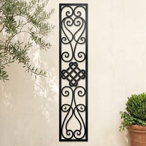 Peut inclure: Un panneau mural rectangulaire et haut en métal noir présentant un motif complexe découpé au laser. Le design se compose de volutes symétriques en haut et en bas, avec un motif central en nœud carré formé de lignes entrelacées.