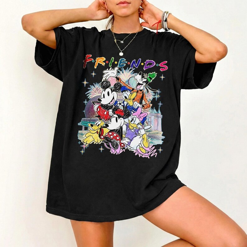 May include: Black t-shirt featuring the word "FRIENDS" in colorful letters above a graphic of Disney characters including Mickey and Minnie Mouse, Donald and Daisy Duck, and Goofy. The design includes fireworks and a castle.