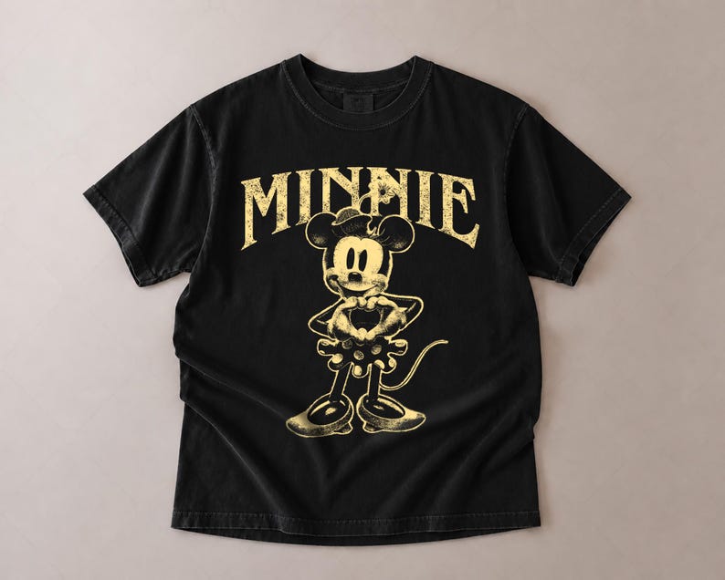 May include: Black t-shirt featuring a distressed graphic of Minnie Mouse with the word "MINNIE" in a vintage font. The design is in a faded yellow color, creating a retro aesthetic. The shirt has short sleeves and a crew neck.