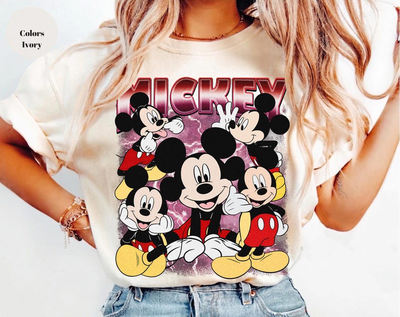 Puede incluir: Camiseta de color marfil con un gr&aacute;fico de Mickey Mouse en varias poses. La palabra "MICKEY" se muestra en una fuente retro burdeos sobre los personajes de dibujos animados. La camiseta tiene mangas cortas.