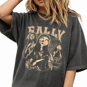 May include: A charcoal gray oversized t-shirt featuring a distressed beige graphic print of the character Sally from The Nightmare Before Christmas. The design includes the text SALLY in a stylized font above three depictions of the character.