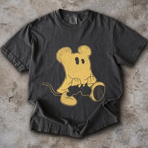 May include: Dark gray t-shirt featuring a vintage-style yellow cartoon mouse graphic. The mouse has large ears, a tail, and is holding a large, round object. The shirt has a crew neck and short sleeves, and is made of a soft, comfortable material.