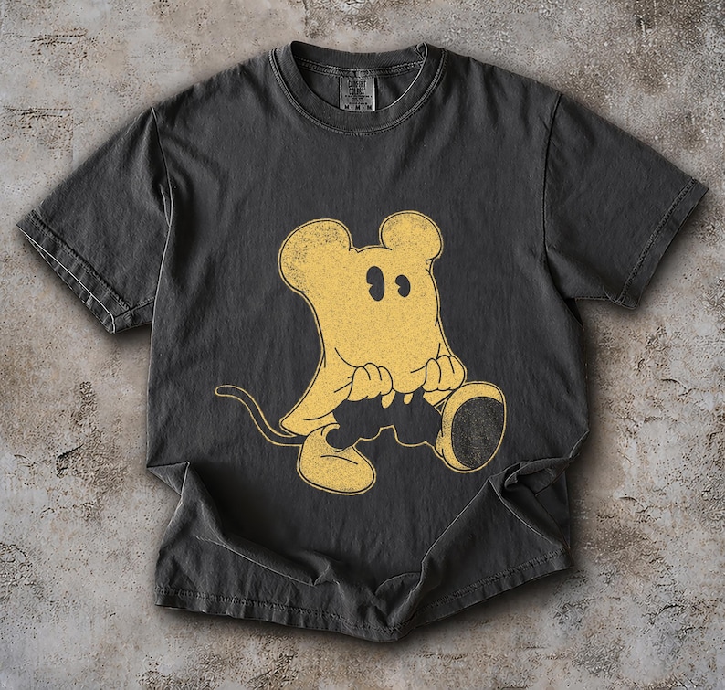 May include: Dark gray t-shirt featuring a vintage-style yellow cartoon mouse graphic. The mouse has large ears, a tail, and is holding a large, round object. The shirt has a crew neck and short sleeves, and is made of a soft, comfortable material.