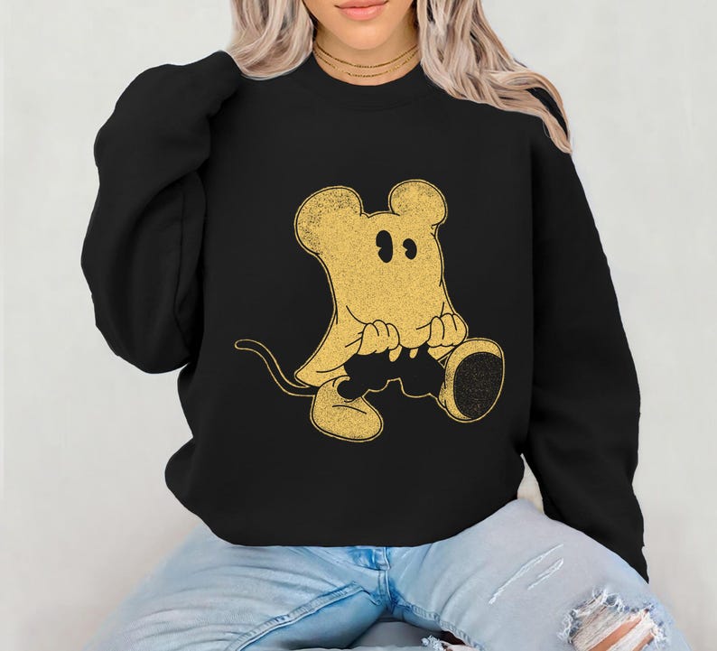 May include: Black sweatshirt featuring a gold-colored cartoon mouse ghost design. The mouse ghost has large ears, a tail, and is sitting down. The sweatshirt is a long-sleeved crew neck.