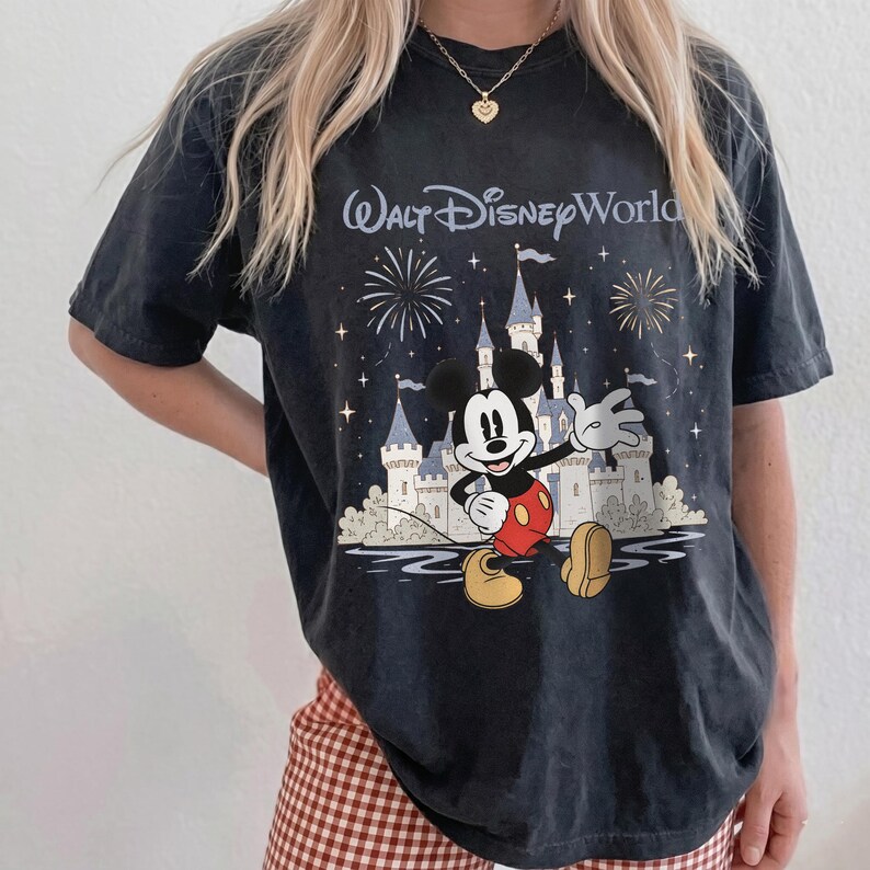 May include: Dark gray t-shirt featuring a graphic of Mickey Mouse in front of Cinderella's castle with fireworks and the text "Walt Disney World". The shirt has a vintage, worn look.
