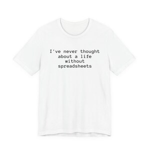May include: A white short-sleeved t-shirt featuring black text printed on the chest that reads, I've never thought about a life without spreadsheets. The garment has a crew neckline and a standard fit, showcasing a simple design.