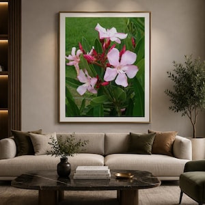 Puede incluir: Una impresión de arte mural rectangular que presenta un grupo de flores de adelfa de color rosa claro con cinco pétalos cada una, rodeadas de hojas lanceoladas de color verde oscuro y capullos rojos sobre un fondo verde suave.