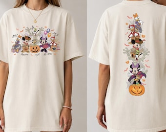 May include: An off-white short-sleeve t-shirt featuring a Halloween-themed graphic of Disney characters in costumes. The front displays a horizontal arrangement of characters, while the back shows a vertical stack of the same characters with a pumpkin.
