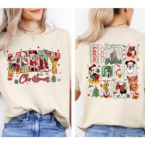 Puede incluir: Una camiseta beige con un gráfico frontal que incluye el texto MERRY CHRISTMAS y personajes de Disney con trajes de Santa. El gráfico trasero muestra una cuadrícula de varios personajes de Disney, un castillo e iconos navideños.