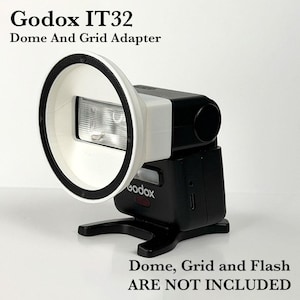 May include: A white Godox IT32 Dome And Grid Adapter attached to a black camera flash unit. The adapter features a circular front rim with black screws. Text on the image reads Godox IT32 Dome And Grid Adapter and Dome, Grid and Flash ARE NOT INCLUDED.
