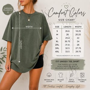May include: An olive green unisex tee shirt with the text "Comfort Colors" and a size chart. The shirt is oversized and relaxed fit. The model is wearing an extra large. The shirt is made of 100% ring spun cotton.