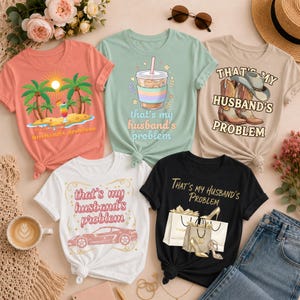 Könnte beinhalten: Fünf T-Shirts mit dem Aufdruck "That's my husband's problem". Die Shirts sind in Koralle, Mintgrün, Weiß, Beige und Schwarz erhältlich. Jedes Shirt hat ein anderes Design, darunter eine Strand- und eine Shopping-Szene.