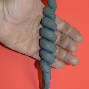 May include: A black metal door handle with a twisted design. The handle has a rounded top and a pointed bottom.