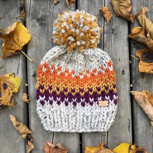 the Sherwoods hat heather oatmeal chunky knit hat with purple, mustard and orange fair-isle pattern and jumbo pompom image 1
