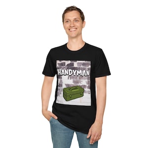 Könnte beinhalten: Schwarzes T-Shirt mit einer Grafik einer grünen Werkzeugkiste und dem Wort "HANDYMAN" in weißen Buchstaben vor einem Backsteinmauer-Hintergrund. Das Shirt ist aus einem weichen, bequemen Material.