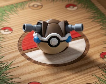 Puede incluir: Un juguete marrón y beige con dos cañones grises y detalles azules, que se asemeja a un personaje de la franquicia Pokemon. Se encuentra sobre una superficie de madera decorada con hierba y diseños de Poké Ball rojos y blancos.