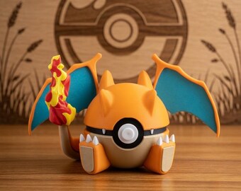 Puede incluir: Figura de Charizard naranja y marrón con alas azules y cola de llama, con diseño de Poké Ball. El fondo es una superficie de madera con un logotipo de Pokémon y otros elementos decorativos.