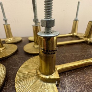May include: Close-up of several brass-colored cabinet pulls with a semi-circular base and a cylindrical post. Each pull has a threaded bolt and nut for installation. The pulls are labeled "MADE IN INDIA".