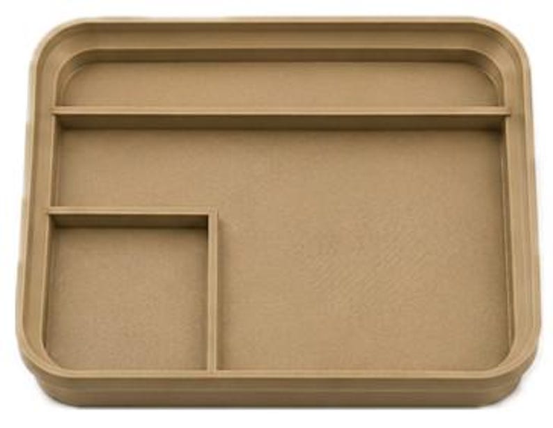 Op de afbeelding: Een rechthoekige, bruin-beige lade met afgeronde hoeken en opstaande randen. Het heeft een vierkant compartiment en een lang, smal compartiment. Het oppervlak heeft een subtiele textuur.