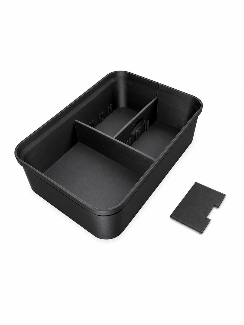 May include: A rectangular black plastic storage tray featuring three internal compartments separated by two removable dividers. The tray has a smooth matte finish and includes one additional small rectangular black divider piece placed outside the main container.