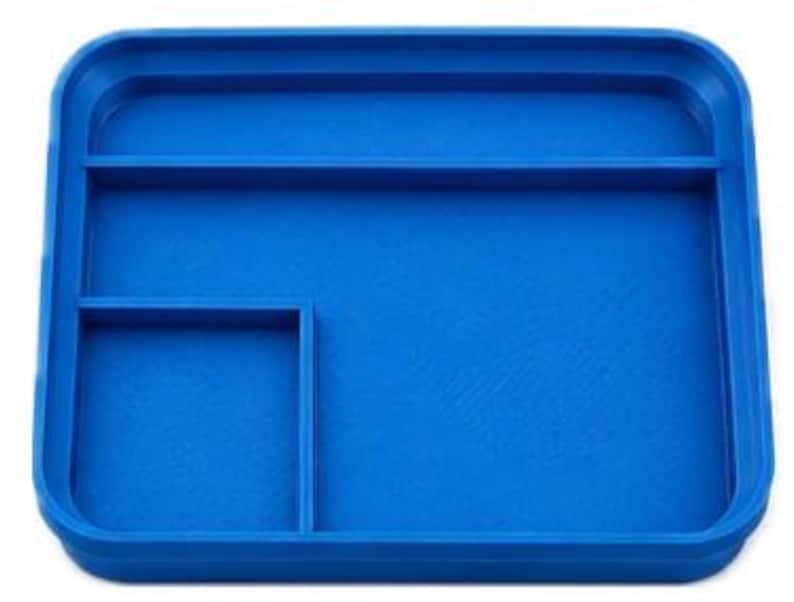 Op de afbeelding: Een helderblauwe rechthoekige tray met afgeronde hoeken en opstaande randen. De tray is verdeeld in drie secties: een groot rechthoekig gebied en twee kleinere compartimenten. Het oppervlak heeft een licht getextureerd uiterlijk.