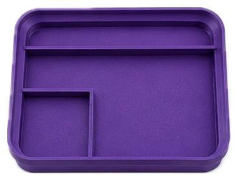 Op de afbeelding: Een rechthoekige, paarse tray met opstaande randen en drie compartimenten. De tray heeft een groot open gedeelte en twee kleinere, verdeelde secties voor organisatie. Het gladde oppervlak is effen, levendig paars.