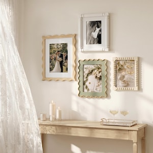 May include: Four rectangular wall frames with varied designs: a light wood scalloped frame, a white fluted frame, a sage green scalloped frame, and a cream-colored beaded frame. Each frame displays a photograph, including wedding scenes and floral arrangements.