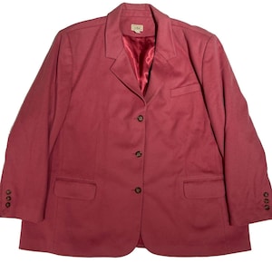 Op de afbeelding: Een oudroze blazer met een ingekeepte revers, drie donkere knopen aan de voorzijde en twee onderste klepzakken. Het kledingstuk heeft een borstzak, lange mouwen met drie kleine knopen aan elke manchet en een gladde, glanzende rode binnenvoering.