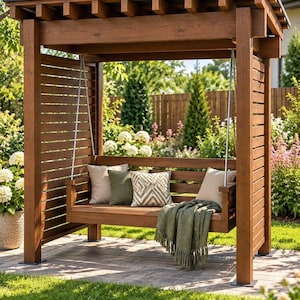 Könnte beinhalten: Eine braune Gartenschaukel aus Holz mit Lamellendach und Seitenwänden. Die Sitzbank ist mit zwei beigen Kissen, einem olivgrünen Kissen und einem gemusterten weiß-grauen Kissen ausgestattet. Eine olivgrüne Decke mit Fransen liegt auf dem Sitz.
