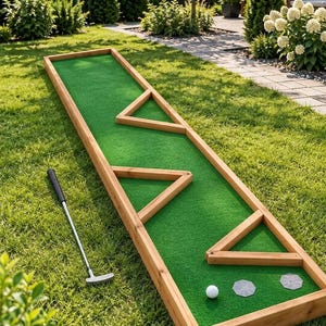 Peut inclure: Un green de mini-golf rectangulaire en bois avec du gazon artificiel vert, trois obstacles triangulaires en bois, deux marqueurs circulaires gris et une balle de golf blanche. Un putter en métal avec un grip noir est posé sur l'herbe.