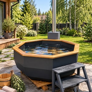 Puede incluir: Un jacuzzi octogonal con exterior gris oscuro mate y borde de madera natural. Cuenta con una chimenea vertical alta de acero inoxidable, un escalón de dos niveles a juego en gris oscuro, un cubo de madera y dos toallas grises enrolladas.