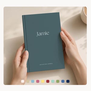 May include: A teal journal with the name "Jamie" in white script. The words "REFLECTION JOURNAL" are printed at the bottom. The journal is held open by two hands.