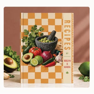 May include: A hardcover cookbook titled RECIPES BY ROSLYN & MARIA featuring a yellow and white checkered background. The cover displays a dark gray mortar and pestle filled with guacamole, surrounded by an avocado, tomato, onion, lime, and chili peppers.